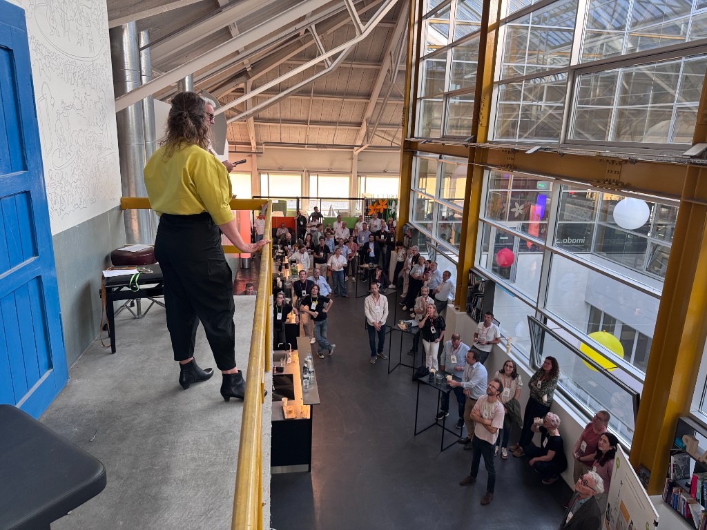A speaker addressing guests from the mezzanine of the workshop.