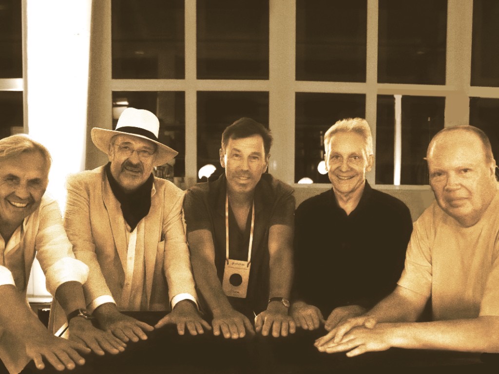 The same founding team, forty years later, recreating that photograph.