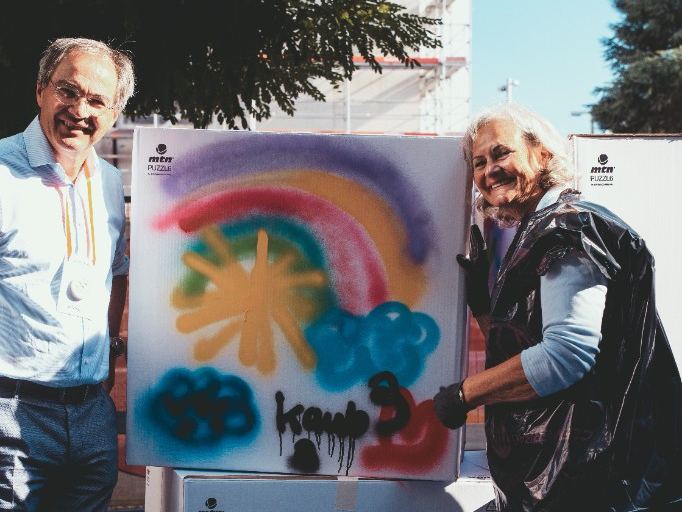 Two people beside a spray-painted panel at the anniversary.